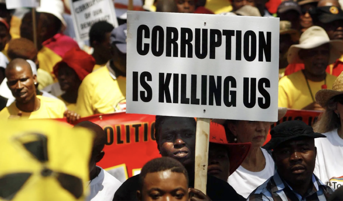 A protestor holds a sign stating 'CORRUPTION IS KILLING US' during a demonstration in South Africa
