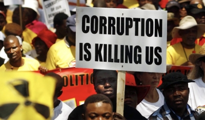 A protestor holds a sign stating 'CORRUPTION IS KILLING US' during a demonstration in South Africa