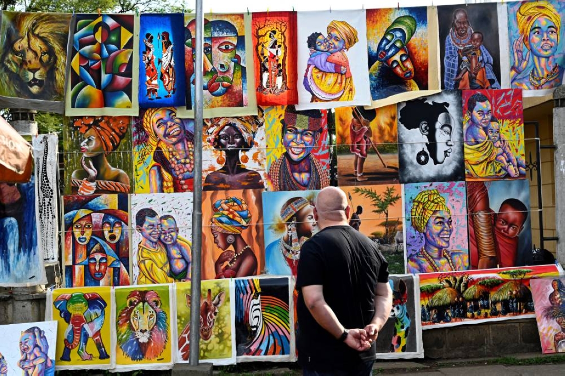 A tourist admiring paintings depicting the "Kenyan colors."