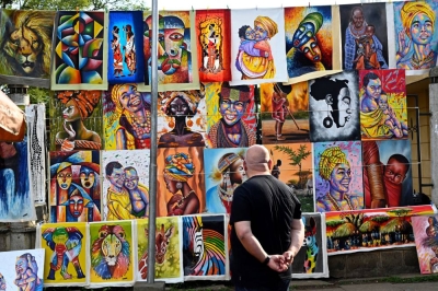 A tourist admiring paintings depicting the "Kenyan colors."